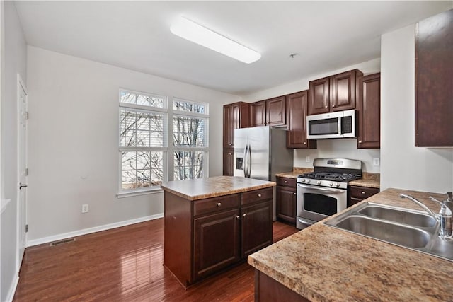 kitchen with a center island, stainless steel appliances, visible vents, dark wood-type flooring, and a sink