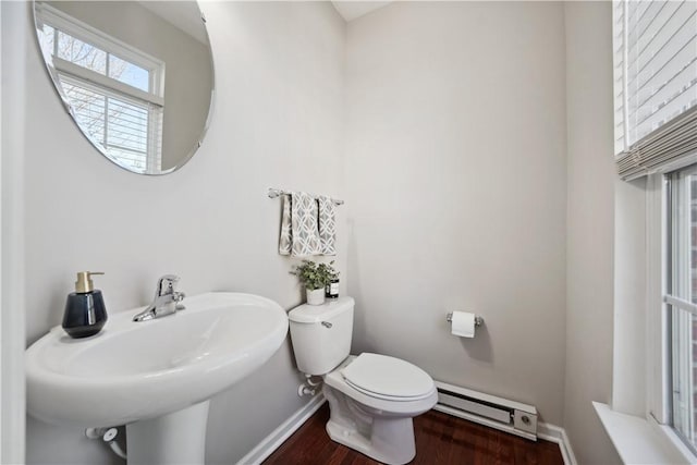 half bathroom featuring toilet, baseboards, baseboard heating, and a sink