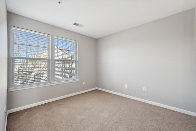 empty room featuring carpet floors, visible vents, and baseboards