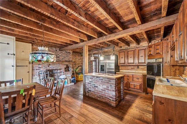 kitchen featuring dark wood-type flooring, a sink, light countertops, beam ceiling, and brown cabinetry