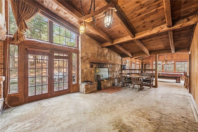 unfurnished living room with wood ceiling, beamed ceiling, carpet floors, wood walls, and high vaulted ceiling