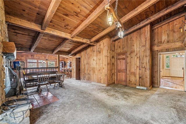 unfurnished room featuring beamed ceiling, wood walls, wooden ceiling, and a wealth of natural light