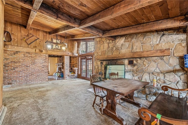 unfurnished dining area with wooden ceiling, a fireplace, french doors, beam ceiling, and carpet