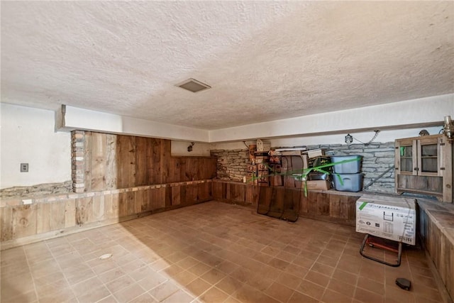 finished basement featuring a textured ceiling and wooden walls