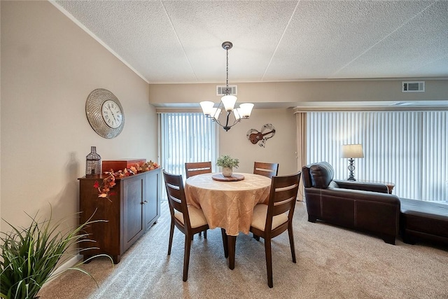 dining space with light carpet, visible vents, a chandelier, and a textured ceiling