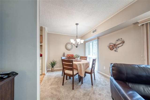 dining space with visible vents, light carpet, a textured ceiling, a chandelier, and baseboards