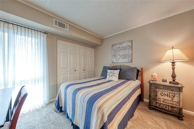 bedroom with a textured ceiling, visible vents, baseboards, a closet, and carpet