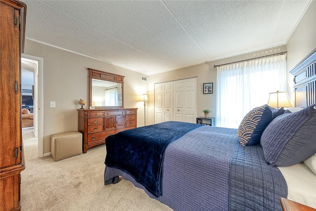 carpeted bedroom featuring a closet, visible vents, crown molding, and a textured ceiling