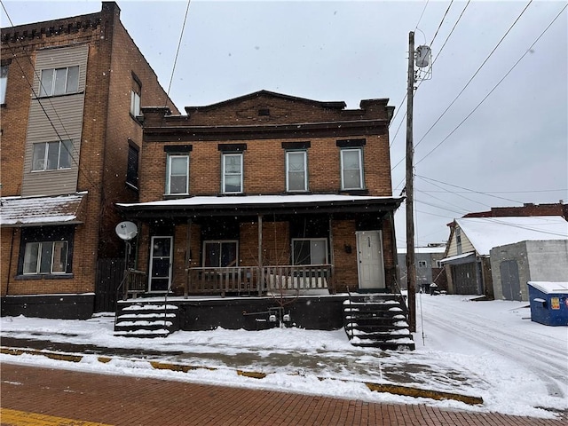 townhome / multi-family property featuring covered porch and brick siding