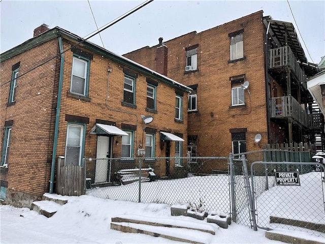 multi unit property featuring a gate, brick siding, and fence