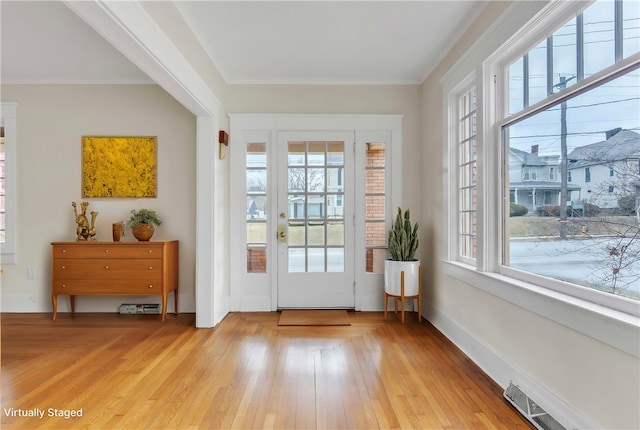 entryway featuring light wood-type flooring, baseboards, visible vents, and crown molding