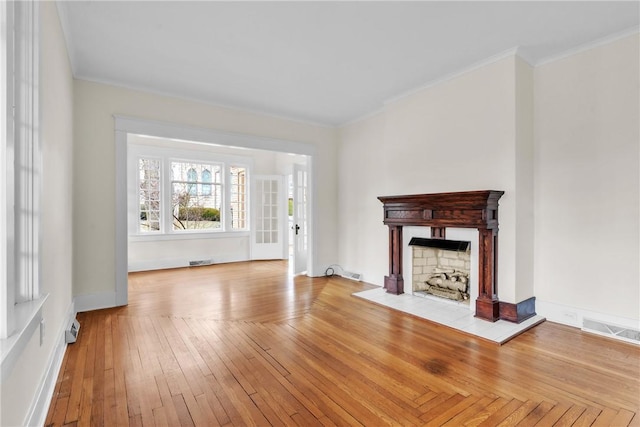 unfurnished living room featuring visible vents, a fireplace, hardwood / wood-style flooring, and crown molding