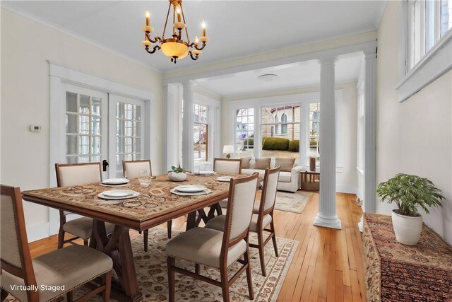 dining space featuring light wood-style floors, decorative columns, and crown molding