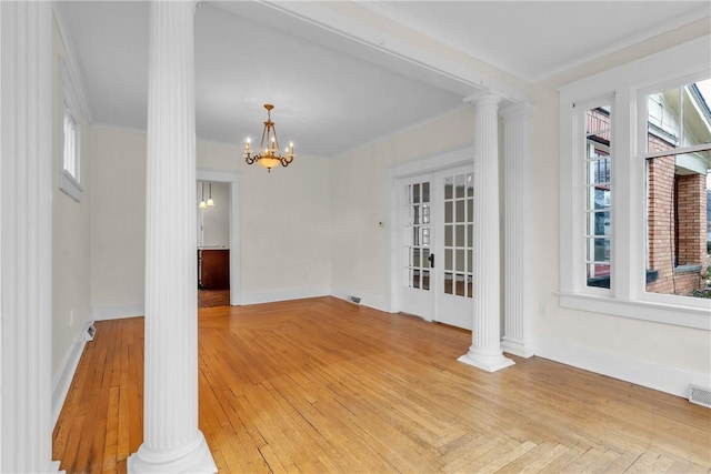 spare room with ornamental molding, baseboards, light wood finished floors, and ornate columns