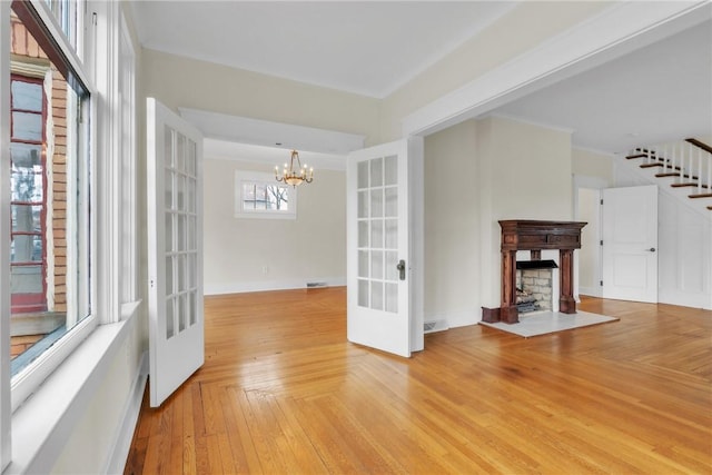 interior space with parquet floors, stairs, french doors, a fireplace, and a notable chandelier