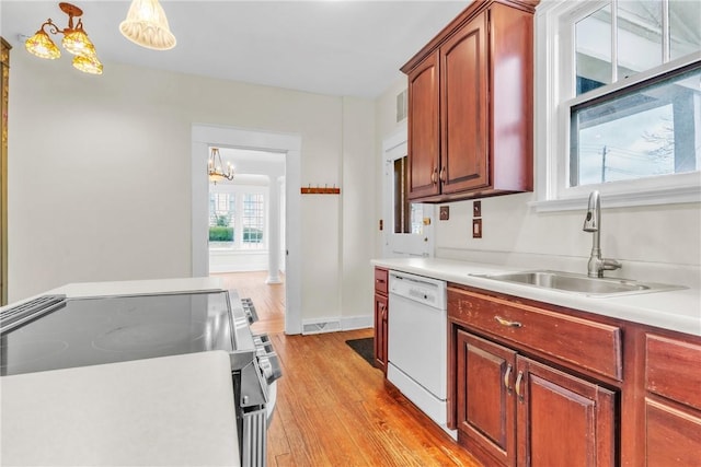 kitchen featuring a sink, white dishwasher, light countertops, and electric stove