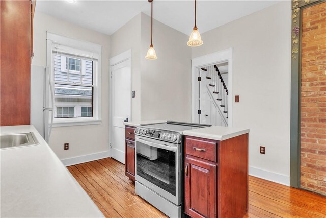 kitchen featuring light countertops, electric range, light wood-type flooring, and baseboards