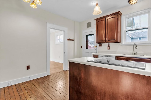 kitchen with a sink, visible vents, light wood-style floors, light countertops, and pendant lighting