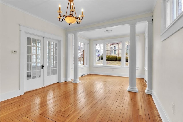 unfurnished dining area featuring light wood-type flooring, crown molding, and ornate columns