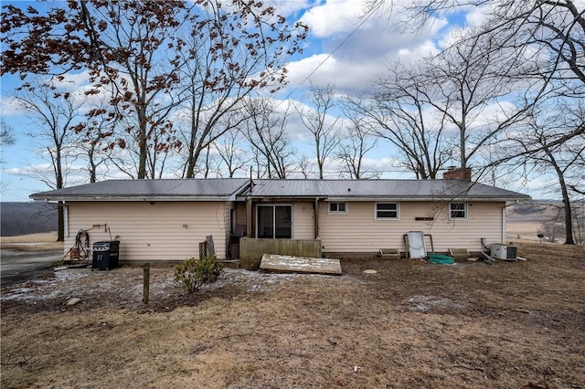 back of property featuring a chimney and central AC unit