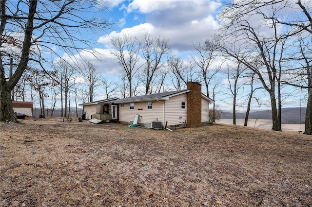 rear view of house with a chimney and central air condition unit