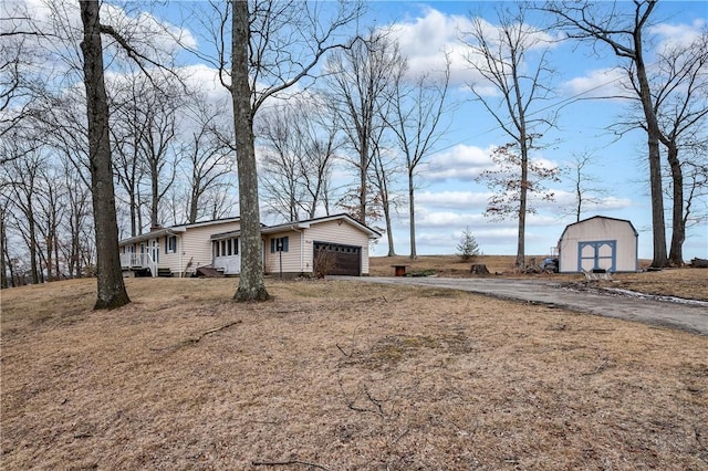 exterior space with an outbuilding, driveway, an attached garage, and a shed