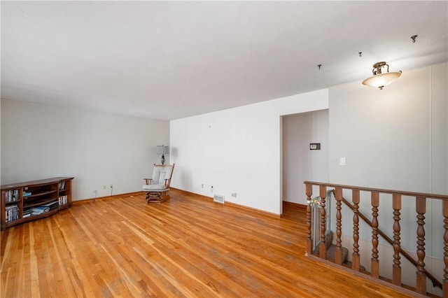 unfurnished room featuring light wood-type flooring, visible vents, and baseboards