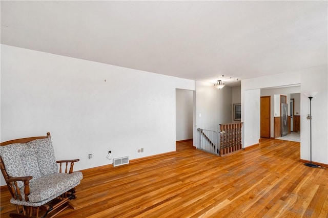 empty room featuring light wood-type flooring, visible vents, and baseboards