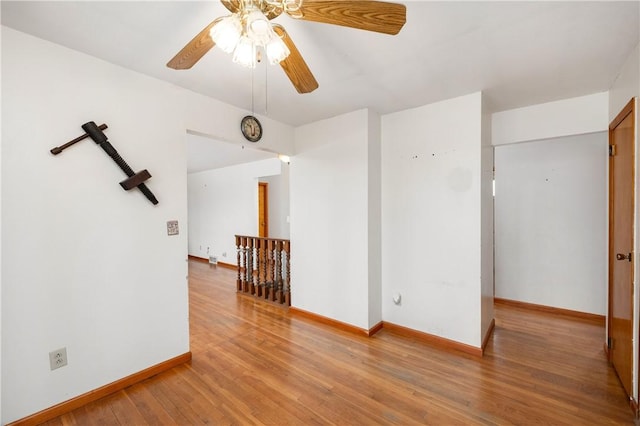 unfurnished room with a ceiling fan, baseboards, and wood finished floors