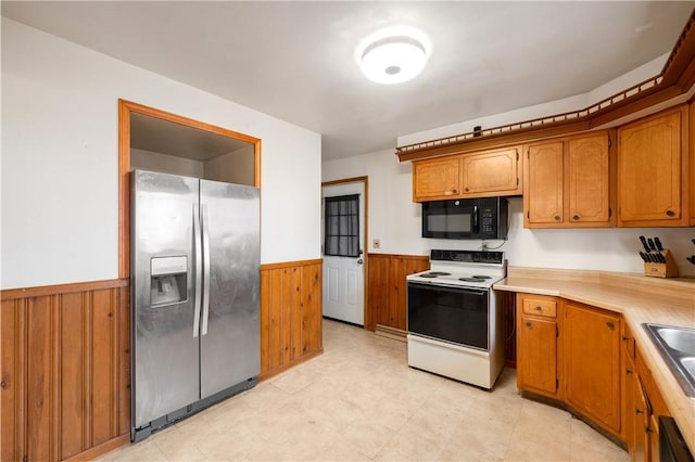 kitchen featuring black microwave, wainscoting, white range with electric cooktop, and stainless steel refrigerator with ice dispenser