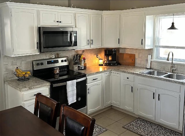 kitchen featuring appliances with stainless steel finishes, white cabinets, a sink, and light tile patterned floors