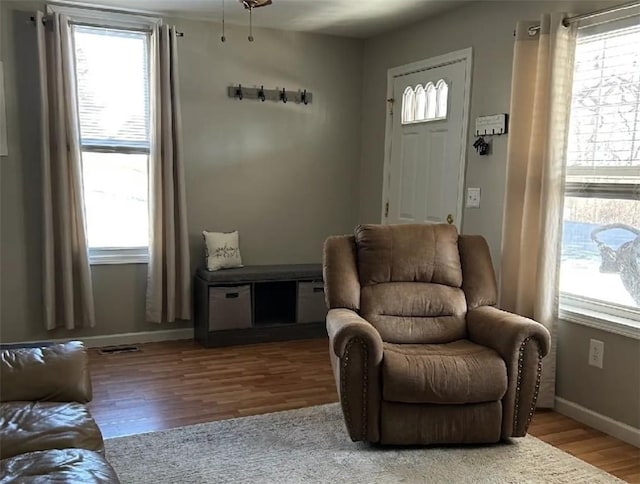 sitting room with baseboards, wood finished floors, visible vents, and a healthy amount of sunlight