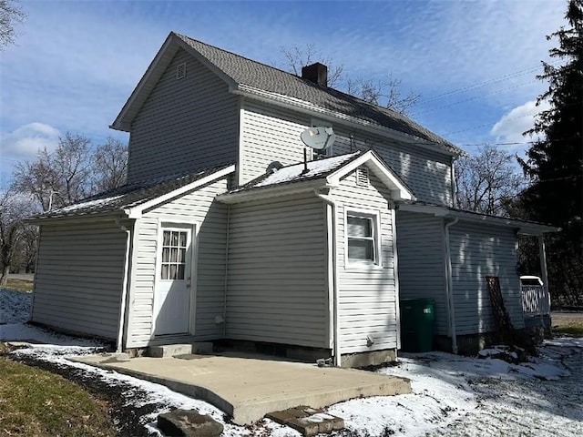 snow covered property with a patio area and a chimney