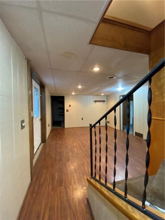 hallway with stairway, wood finished floors, and a paneled ceiling