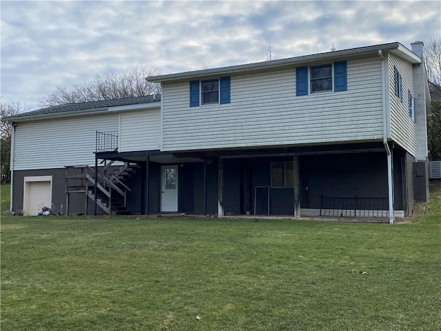 rear view of house with a lawn, a deck, an attached garage, and stairs