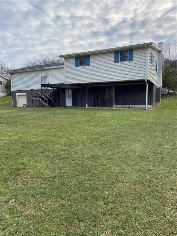 rear view of property with central AC unit, stairway, and a lawn