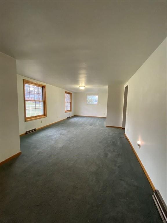 spare room with dark colored carpet, visible vents, and baseboards