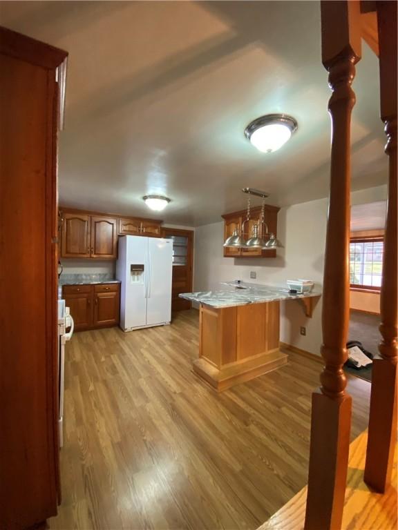 kitchen featuring white fridge with ice dispenser, light wood-type flooring, a peninsula, and stove