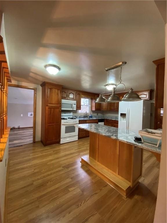 kitchen featuring white appliances, brown cabinets, wood finished floors, and light countertops