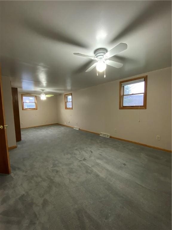 carpeted empty room with ceiling fan, visible vents, and baseboards