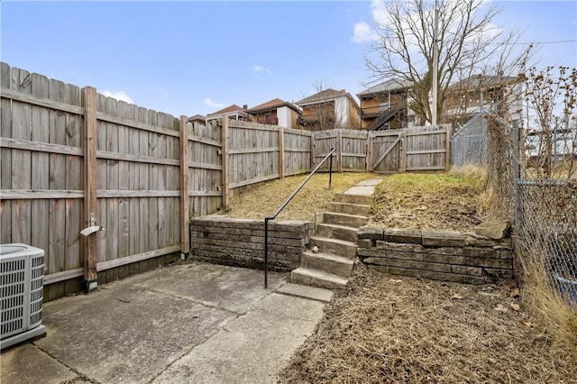 view of yard featuring a gate, fence, central AC unit, and a patio