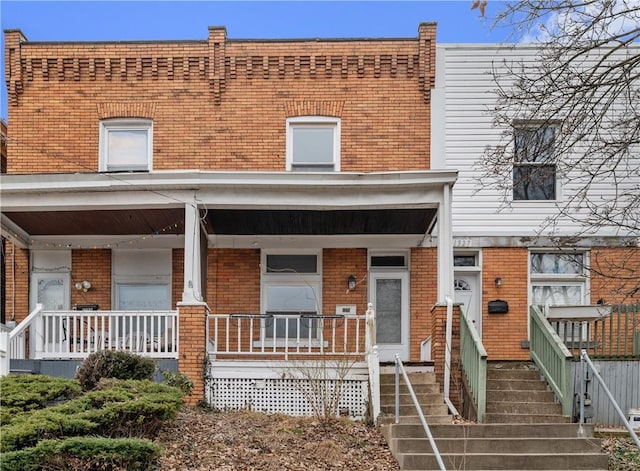 view of property featuring a porch and brick siding