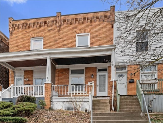 townhome / multi-family property featuring a porch and brick siding