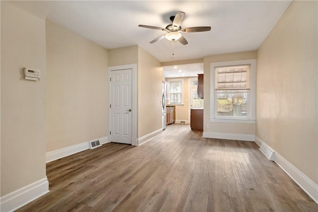 spare room featuring wood finished floors, visible vents, and baseboards