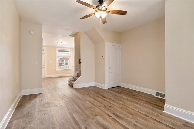 additional living space with ceiling fan, wood finished floors, visible vents, baseboards, and stairs