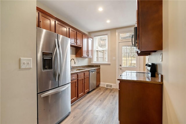 kitchen featuring light wood finished floors, baseboards, visible vents, stainless steel appliances, and a sink