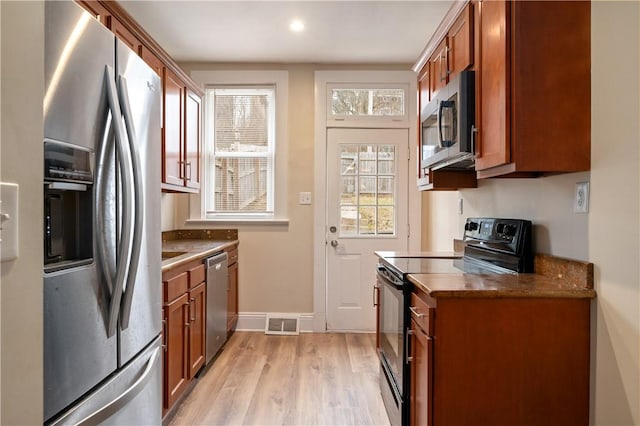 kitchen featuring brown cabinets, visible vents, appliances with stainless steel finishes, light wood-type flooring, and baseboards