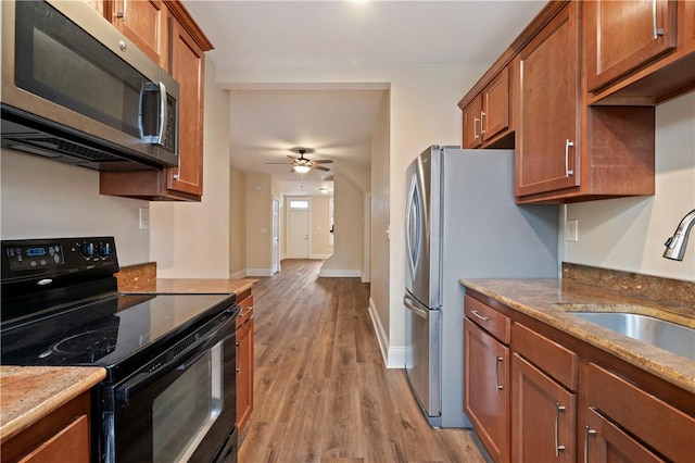 kitchen featuring brown cabinets, stainless steel microwave, light wood-style flooring, and electric range