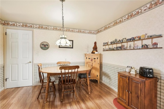 dining room with a wainscoted wall, light wood-type flooring, baseboards, and wallpapered walls