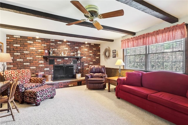 living room featuring ceiling fan, a wainscoted wall, a brick fireplace, beam ceiling, and carpet